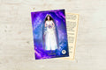 A prayer card featuring the Greek Goddess Selene, depicted with a white dress and holding a golden orb, against a purple background. There is a poem and a symbol on the back of the card.