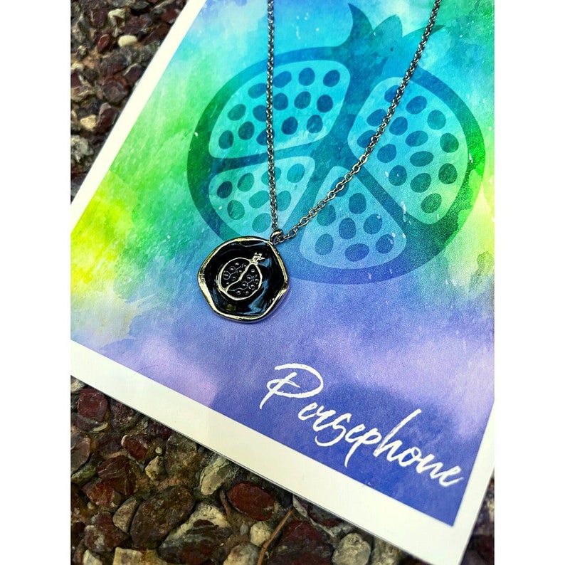 Silver pomegranate necklace on colorful background representing Goddess Persephone and the Underworld.