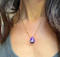 A selection of colorful necklaces with eye designs displayed on a table with a paper featuring illustrations of goddesses.