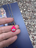 A selection of colorful necklaces with eye designs displayed on a table with a paper featuring illustrations of goddesses.