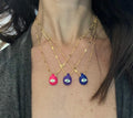 A selection of colorful necklaces with eye designs displayed on a table with a paper featuring illustrations of goddesses.