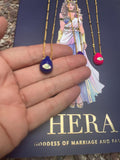 A selection of colorful necklaces with eye designs displayed on a table with a paper featuring illustrations of goddesses.