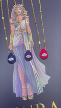 A selection of colorful necklaces with eye designs displayed on a table with a paper featuring illustrations of goddesses.