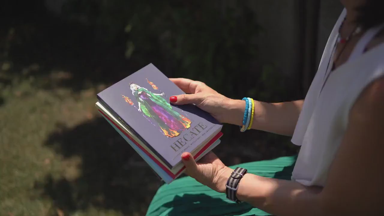 Cover of a booklet titled 'Goddess Hekate Affirmations' featuring a green-colored illustration of a female figure with a crown and holding a staff with two torches, against a purple and blue background with text.