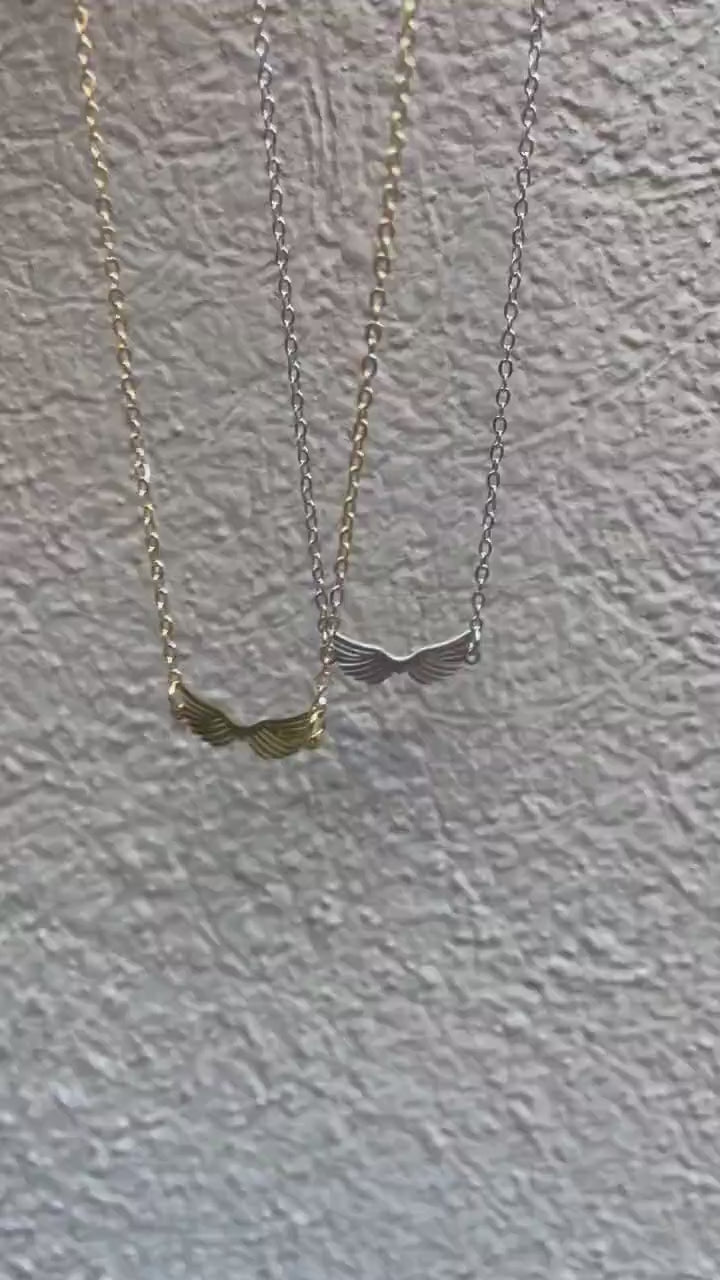 A stainless steel necklace with a winged design, displayed on a tag with an illustration of Hermes, the Greek God of commerce, wealth, and communication.