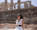 A woman in a white dress sitting in front of a ancient ruins-like background, with text overlay 'Ready to discover the Goddess within?'.
